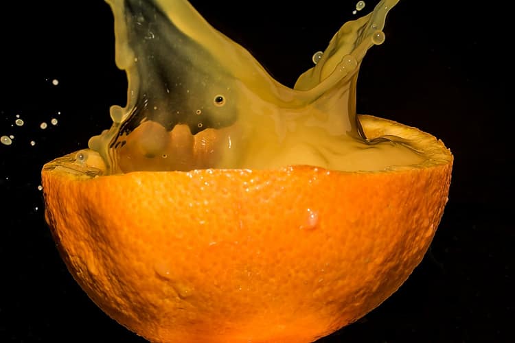 Half an orange with splashing juice