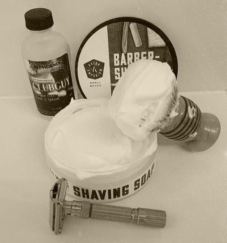 Traditional Shaving Setup with Safety Razor, Brush, Lathered Soap, and Aftershave.